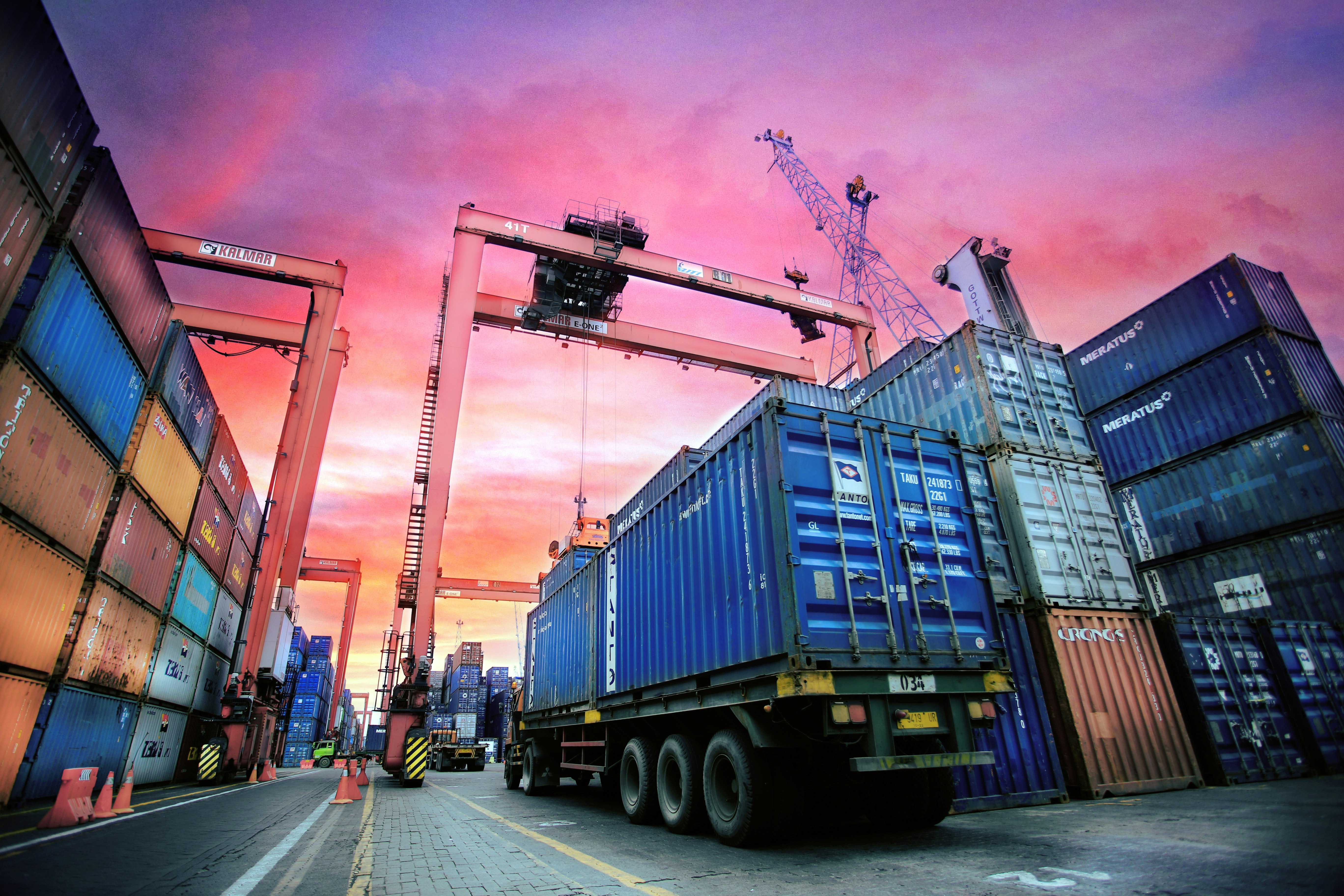 Shipping containers stacked at a busy port at sunset